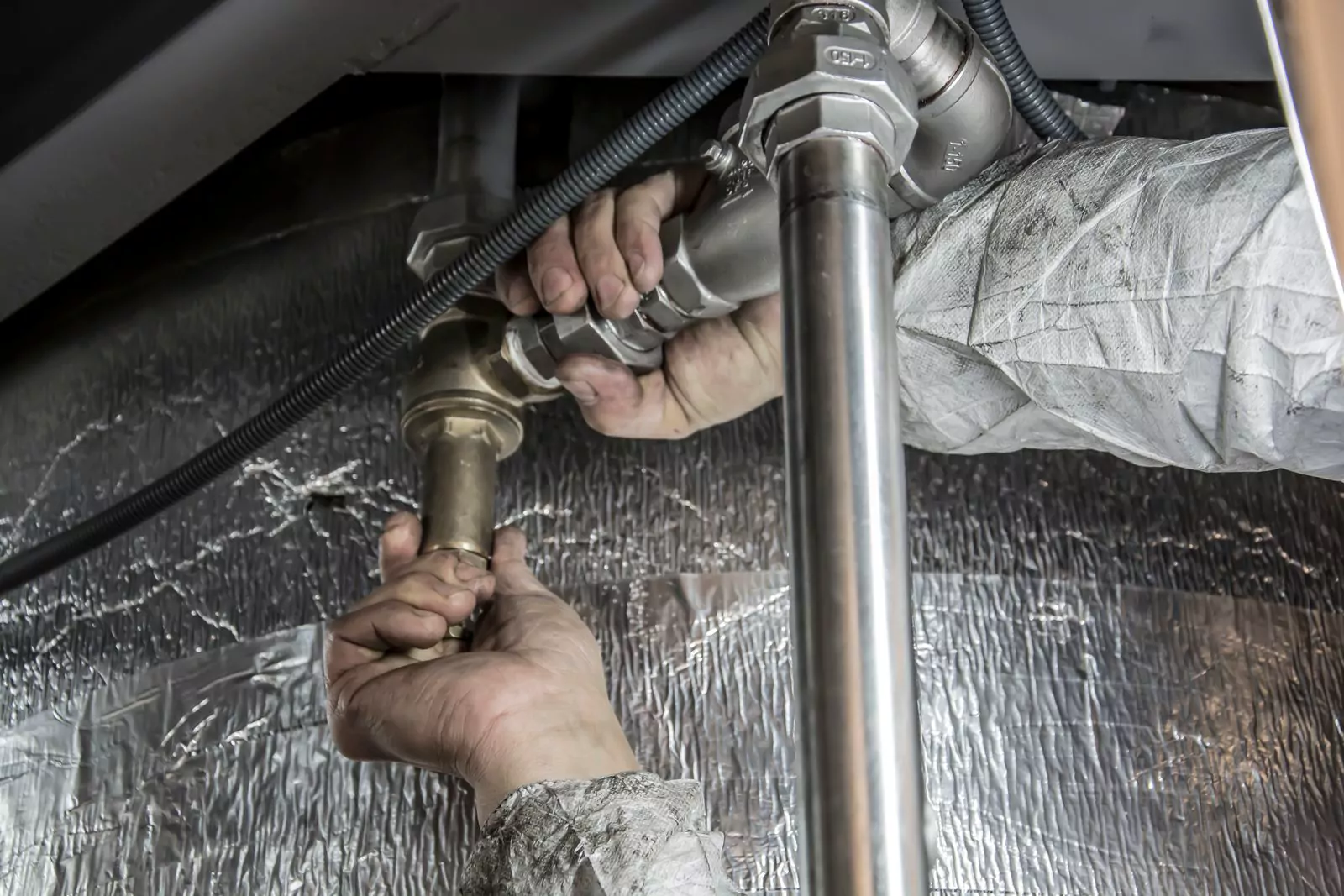Tradesperson connecting industrial pipework